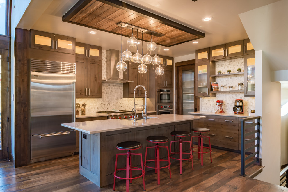 Design ideas for a mid-sized contemporary l-shaped kitchen in Denver with a farmhouse sink, shaker cabinets, medium wood cabinets, soapstone benchtops, beige splashback, ceramic splashback, stainless steel appliances, medium hardwood floors and with island.