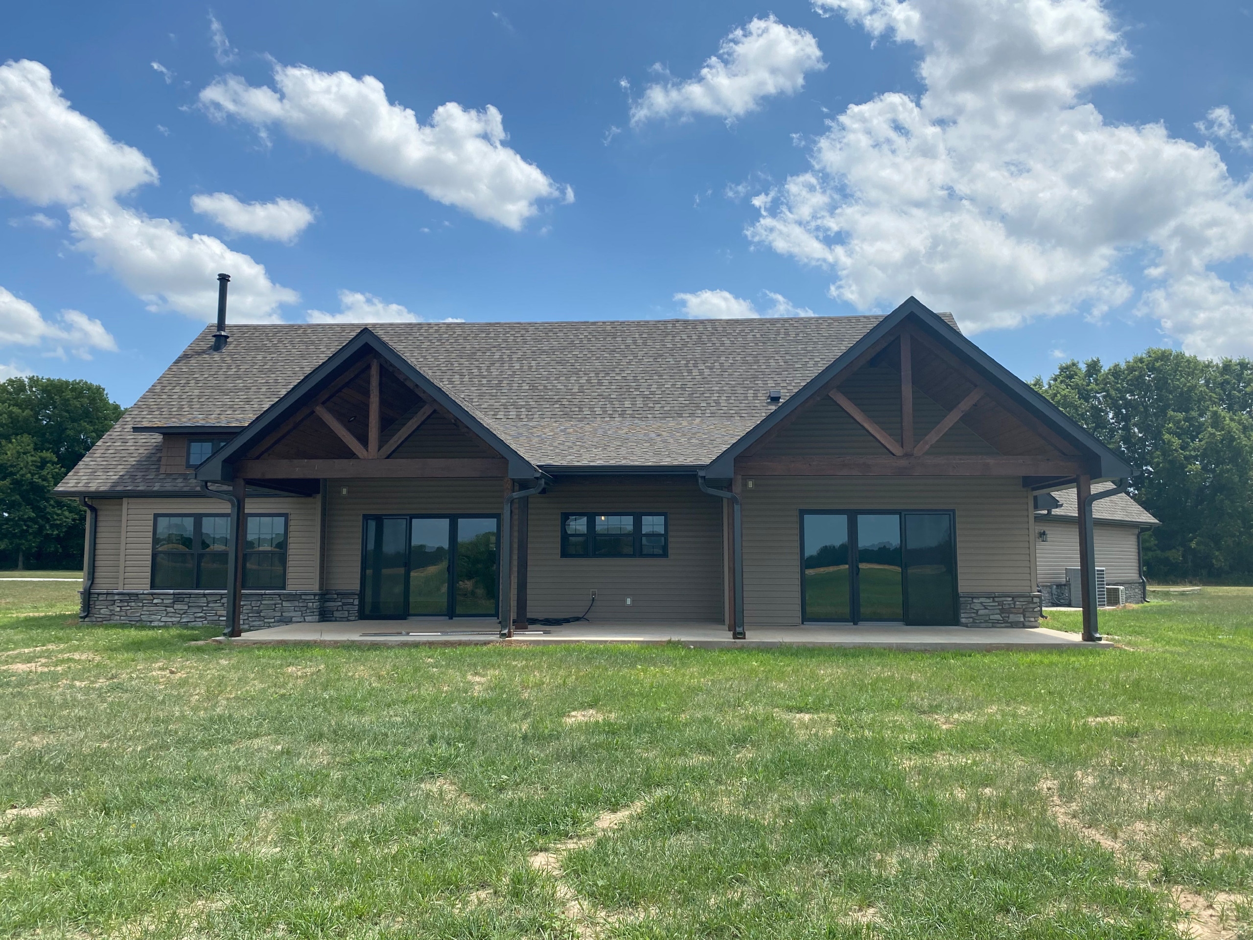 Back side of home with two covered patios, lap siding, rock accent, and cedar be