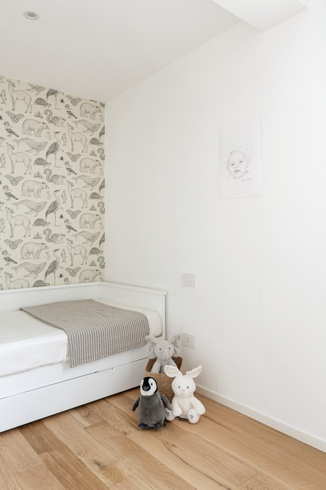 На фото: нейтральная детская среднего размера в скандинавском стиле с спальным местом, белыми стенами, светлым паркетным полом и обоями на стенах