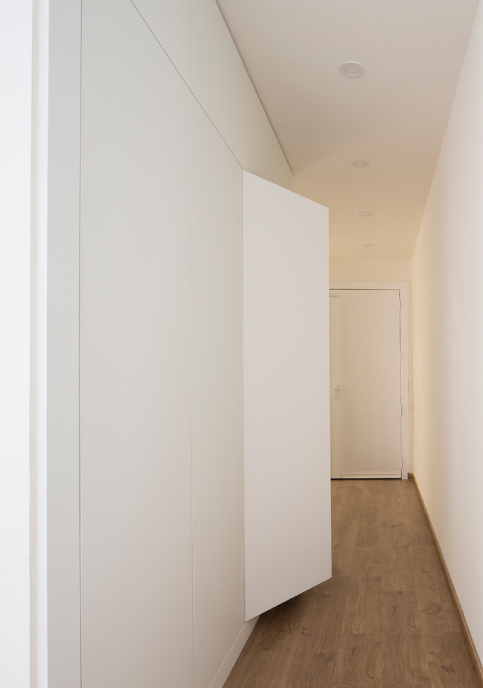 Photo of a mid-sized modern hallway with white walls and medium hardwood floors.