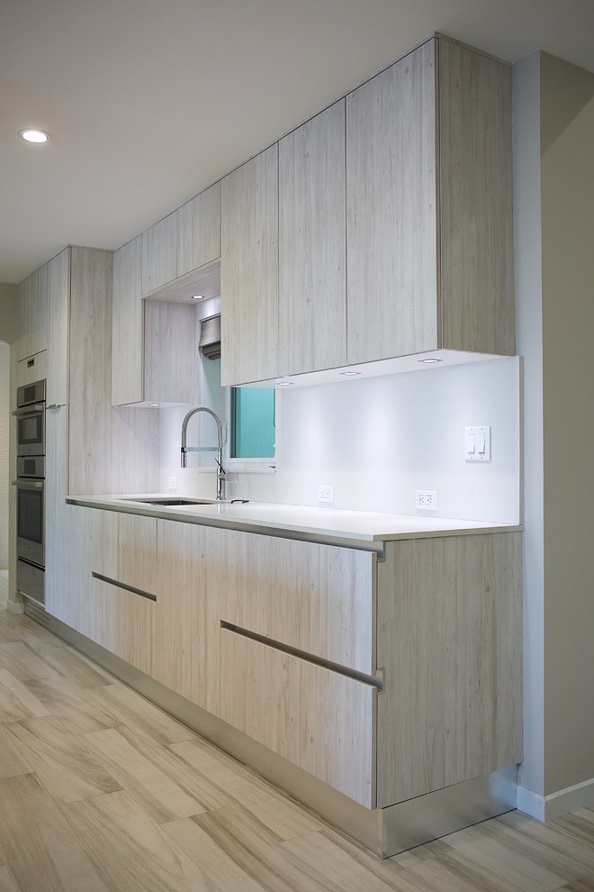 This is an example of a large modern open plan kitchen in Paris with an integrated sink, open cabinets, light wood cabinets, granite benchtops, panelled appliances and with island.