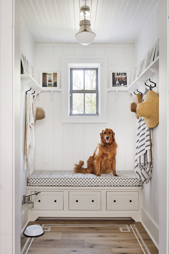 Example of a beach style medium tone wood floor mudroom design in Jacksonville with white walls