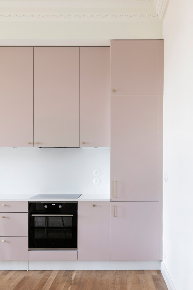 Inredning av ett modernt mellanstort vit linjärt vitt kök med öppen planlösning, med en undermonterad diskho, bänkskiva i kvartsit, vitt stänkskydd, svarta vitvaror, ljust trägolv, luckor med profilerade fronter och brunt golv