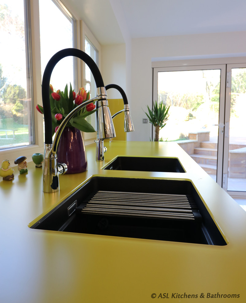 Design ideas for a large modern single-wall open plan kitchen in Other with an undermount sink, flat-panel cabinets, yellow cabinets, glass benchtops, yellow splashback, glass sheet splashback, panelled appliances, porcelain floors, with island, white floor and multi-coloured benchtop.