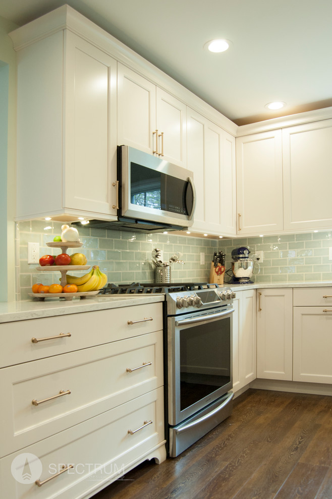 Inspiration for a mid-sized transitional l-shaped dark wood floor eat-in kitchen remodel in Chicago with a drop-in sink, raised-panel cabinets, white cabinets, granite countertops, green backsplash, subway tile backsplash, stainless steel appliances and an island