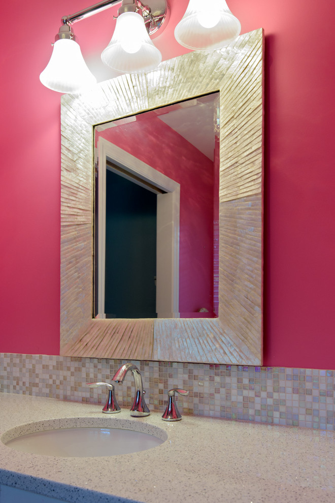 This is an example of a mid-sized transitional kids bathroom in New York with a drop-in sink, flat-panel cabinets, medium wood cabinets, engineered quartz benchtops, a corner shower, a one-piece toilet, multi-coloured tile, glass tile, pink walls, an alcove tub and ceramic floors.