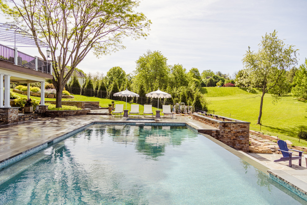 Großer Klassischer Infinity-Pool hinter dem Haus in rechteckiger Form mit Pool-Gartenbau und Natursteinplatten in Wilmington