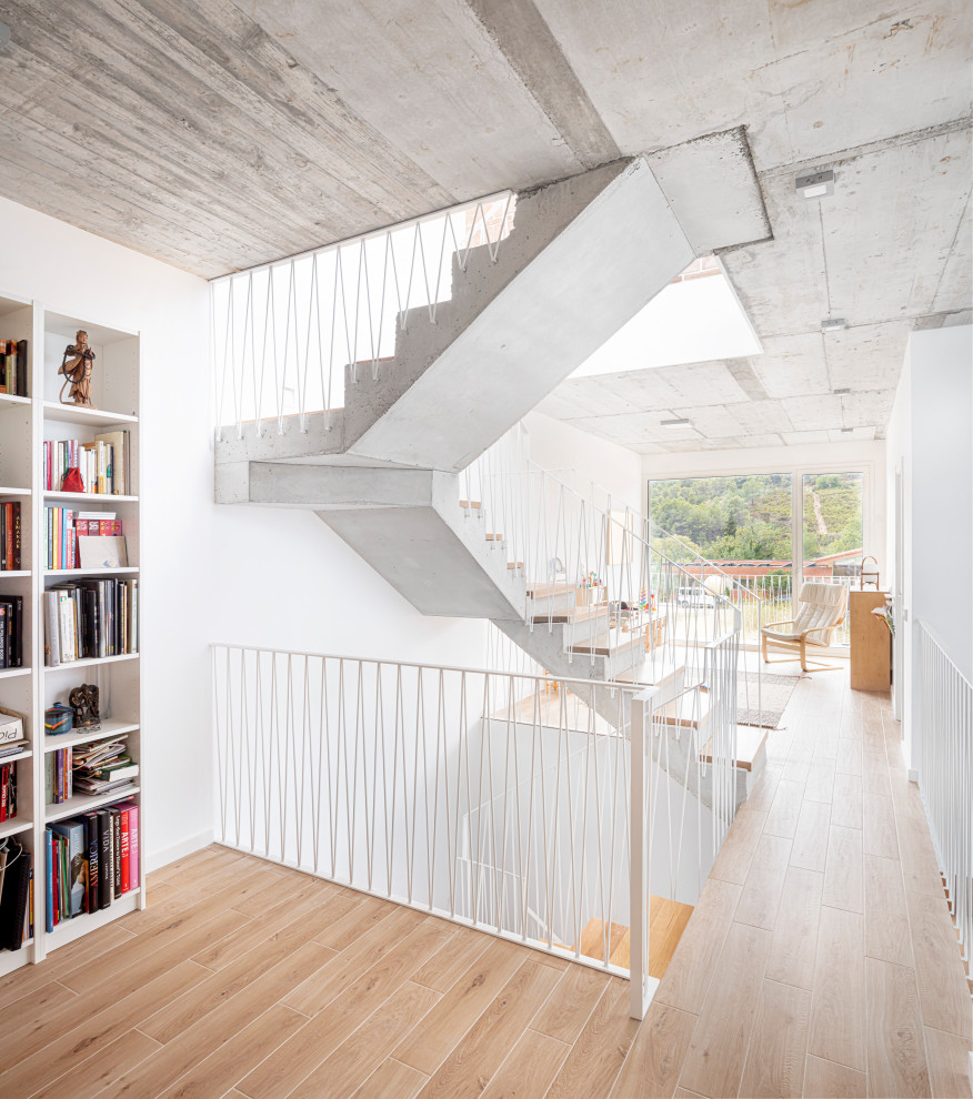 Design ideas for a mid-sized contemporary wood u-shaped staircase in Other with concrete risers and metal railing.