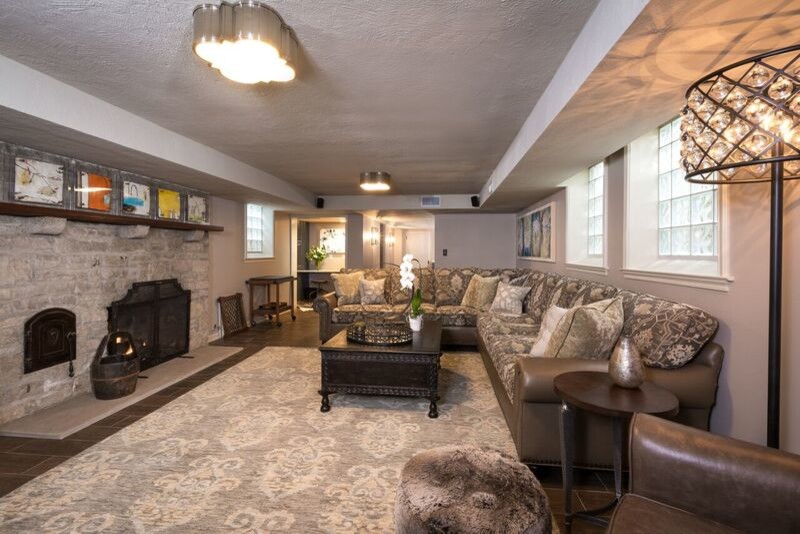 This is an example of a mid-sized arts and crafts fully buried basement in Columbus with beige walls, porcelain floors, a standard fireplace and a stone fireplace surround.