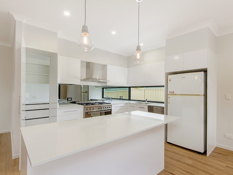Design ideas for a mid-sized contemporary galley open plan kitchen in Gold Coast - Tweed with a double-bowl sink, flat-panel cabinets, white cabinets, granite benchtops, stainless steel appliances, light hardwood floors and with island.
