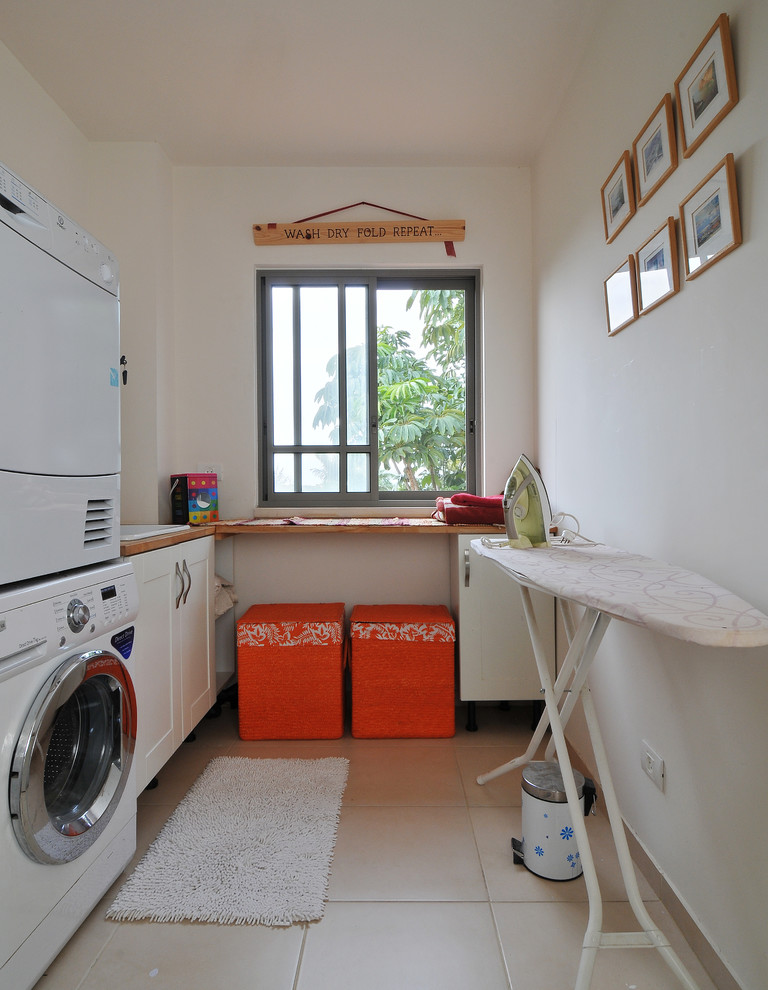 Inspiration for a contemporary laundry room in Tel Aviv with a stacked washer and dryer and white walls.