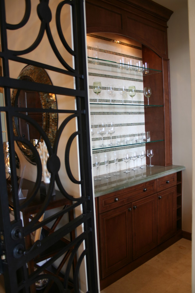 Photo of a small traditional single-wall wet bar in Miami with raised-panel cabinets, medium wood cabinets, travertine floors, soapstone benchtops and mosaic tile splashback.