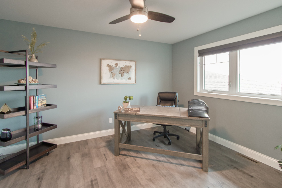 Foto di uno studio con pareti grigie, pavimento in legno massello medio, scrivania autoportante e pavimento grigio
