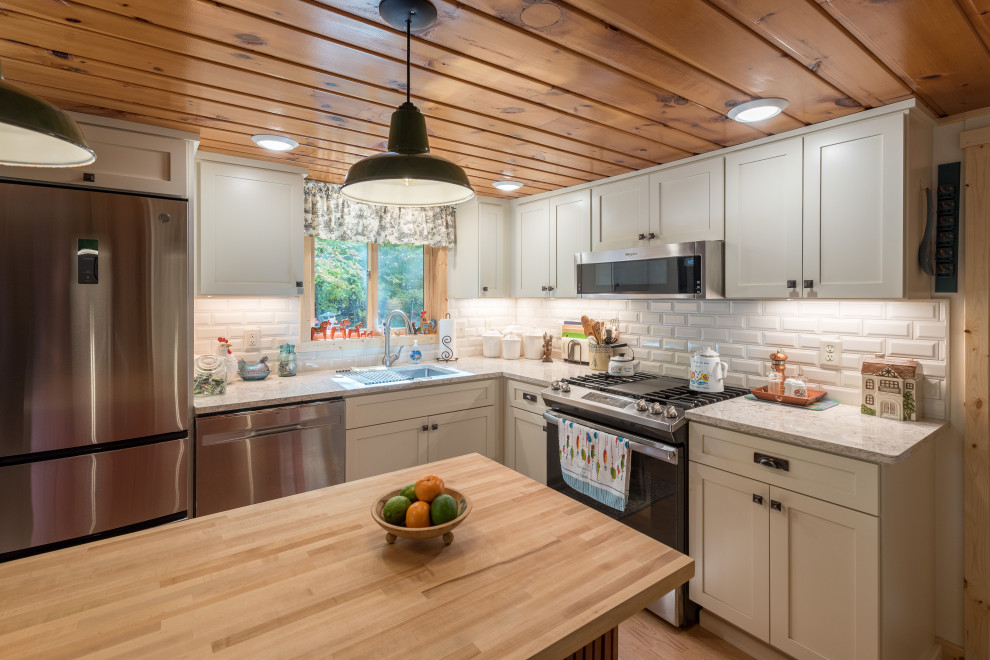 Photo of a small eclectic l-shaped eat-in kitchen in Minneapolis with an undermount sink, shaker cabinets, white cabinets, quartz benchtops, white splashback, subway tile splashback, stainless steel appliances, laminate floors, with island, beige floor and beige benchtop.