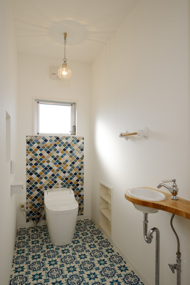 Immagine di un piccolo bagno di servizio nordico con WC monopezzo, piastrelle multicolore, piastrelle in ceramica, pareti bianche, pavimento con piastrelle in ceramica, pavimento blu, soffitto in carta da parati e carta da parati