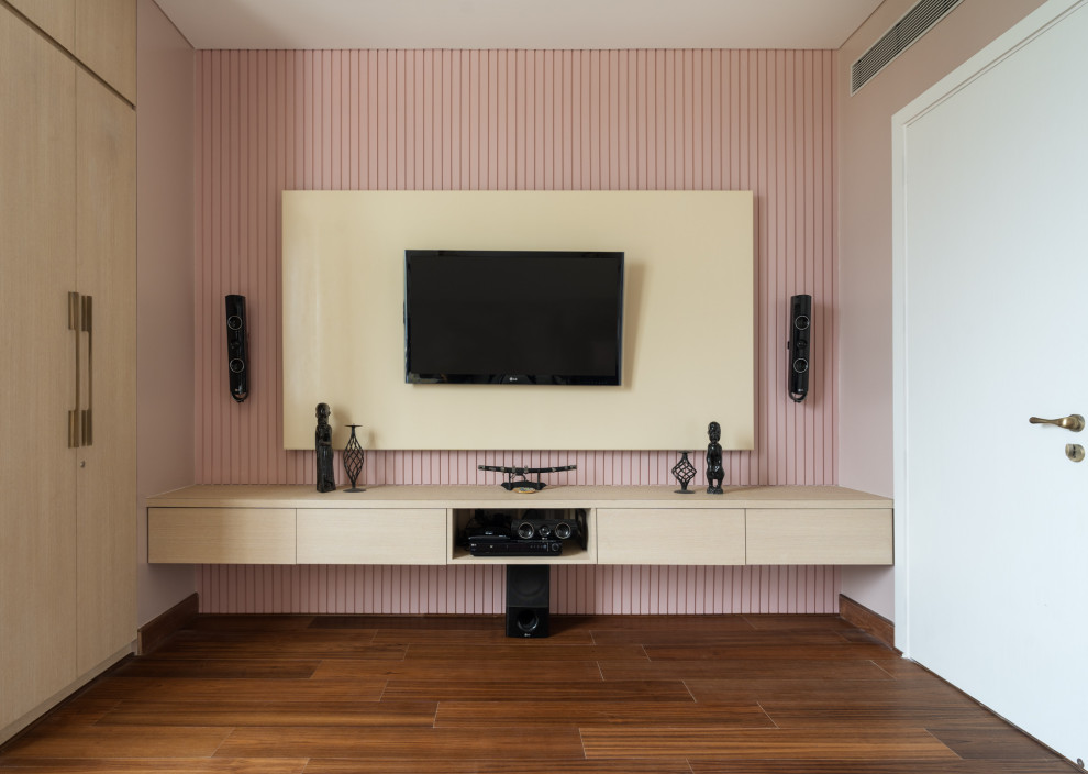 Cette image montre une salle de cinéma minimaliste ouverte avec un mur rose et un téléviseur fixé au mur.