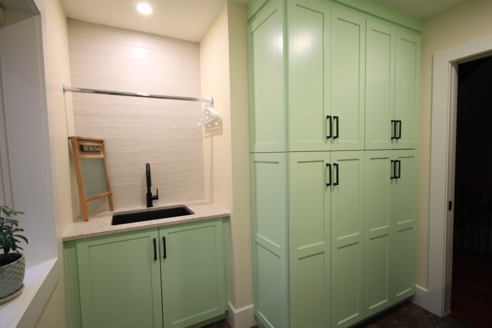 Inspiration for a large modern galley dedicated laundry room in Other with an undermount sink, shaker cabinets, green cabinets, solid surface benchtops, white splashback, subway tile splashback, white walls, vinyl floors, a side-by-side washer and dryer, brown floor and green benchtop.