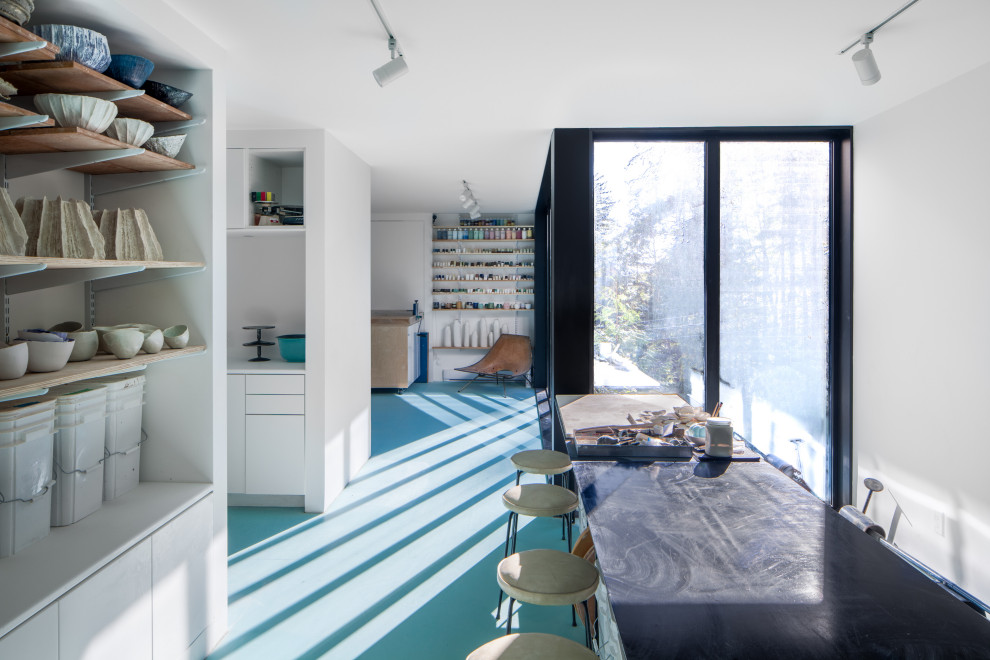 На фото: домашняя мастерская в современном стиле с белыми стенами, бетонным полом и синим полом с