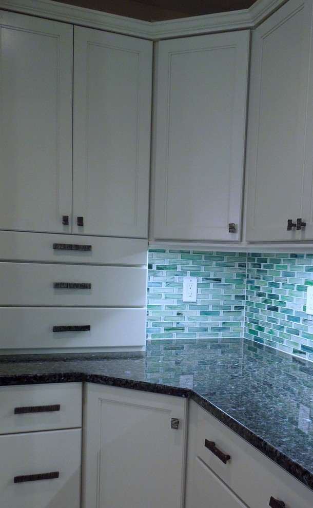Photo of a mid-sized beach style u-shaped open plan kitchen in Charleston with an undermount sink, recessed-panel cabinets, white cabinets, recycled glass benchtops, green splashback, glass tile splashback, stainless steel appliances, ceramic floors and with island.