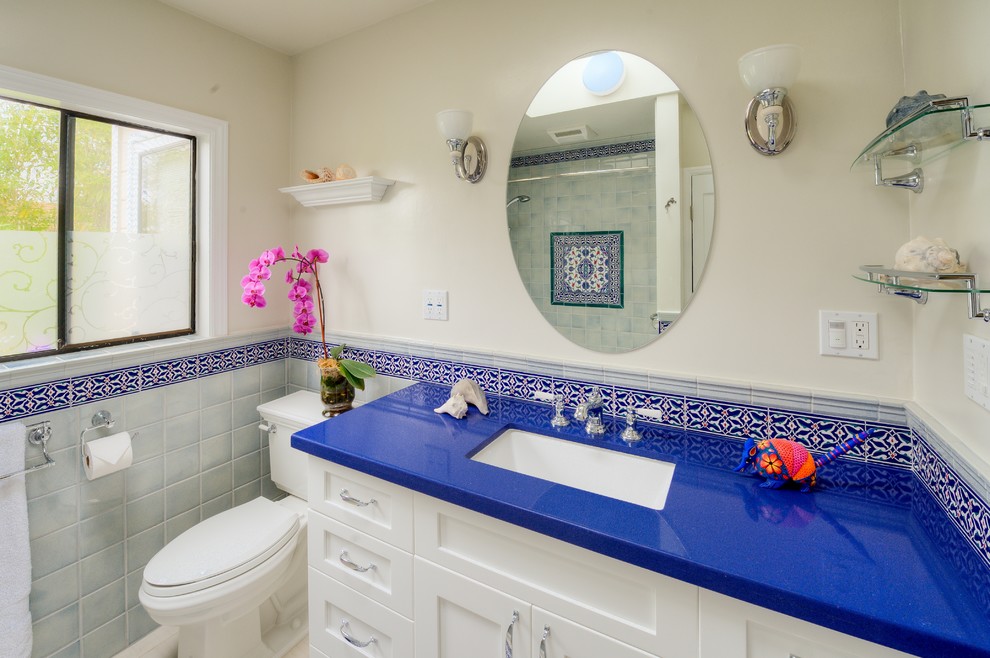 Photo of a mid-sized mediterranean 3/4 bathroom in Los Angeles with an undermount sink, shaker cabinets, white cabinets, an open shower, blue tile, red tile, white tile, ceramic tile, white walls, engineered quartz benchtops, a hinged shower door, ceramic floors, multi-coloured floor, an alcove tub, a two-piece toilet and blue benchtops.