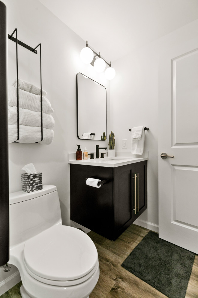 Идея дизайна: маленькая ванная комната в стиле неоклассика (современная классика) с фасадами с утопленной филенкой, темными деревянными фасадами, душем в нише, унитазом-моноблоком, белой плиткой, керамогранитной плиткой, белыми стенами, паркетным полом среднего тона, душевой кабиной, врезной раковиной, столешницей из искусственного кварца, коричневым полом, душем с раздвижными дверями, белой столешницей, тумбой под одну раковину и подвесной тумбой для на участке и в саду
