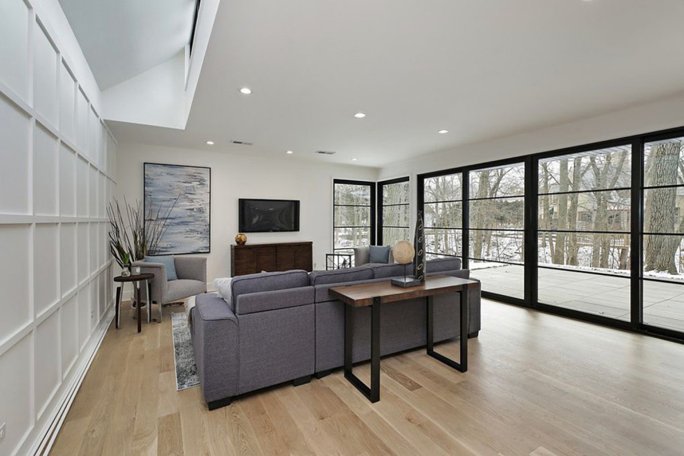 Esempio di un soggiorno minimalista di medie dimensioni e aperto con sala formale, parquet chiaro, TV a parete e soffitto a volta