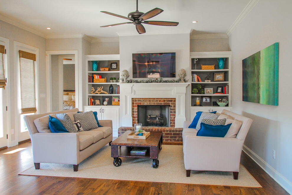 Photo of a mid-sized traditional open concept living room in Nashville with grey walls, dark hardwood floors, a standard fireplace, a brick fireplace surround, a wall-mounted tv and brown floor.