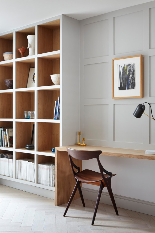 This is an example of a contemporary home office in Essex with grey walls, light hardwood floors, a built-in desk, beige floor and panelled walls.