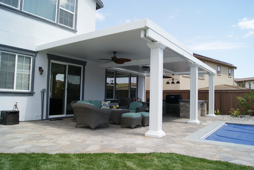 Mid-sized contemporary backyard patio in Sacramento with an outdoor kitchen, natural stone pavers and a roof extension.