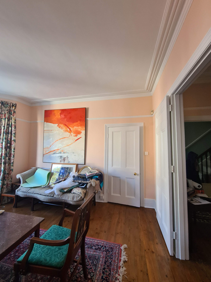 На фото: большая гостиная-столовая в классическом стиле с оранжевыми стенами, темным паркетным полом, стандартным камином, фасадом камина из металла, коричневым полом и многоуровневым потолком с