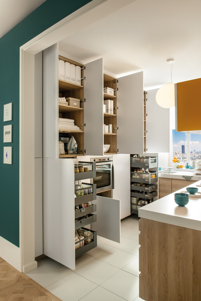 Small contemporary l-shaped kitchen in London with white cabinets, stainless steel appliances and ceramic floors.