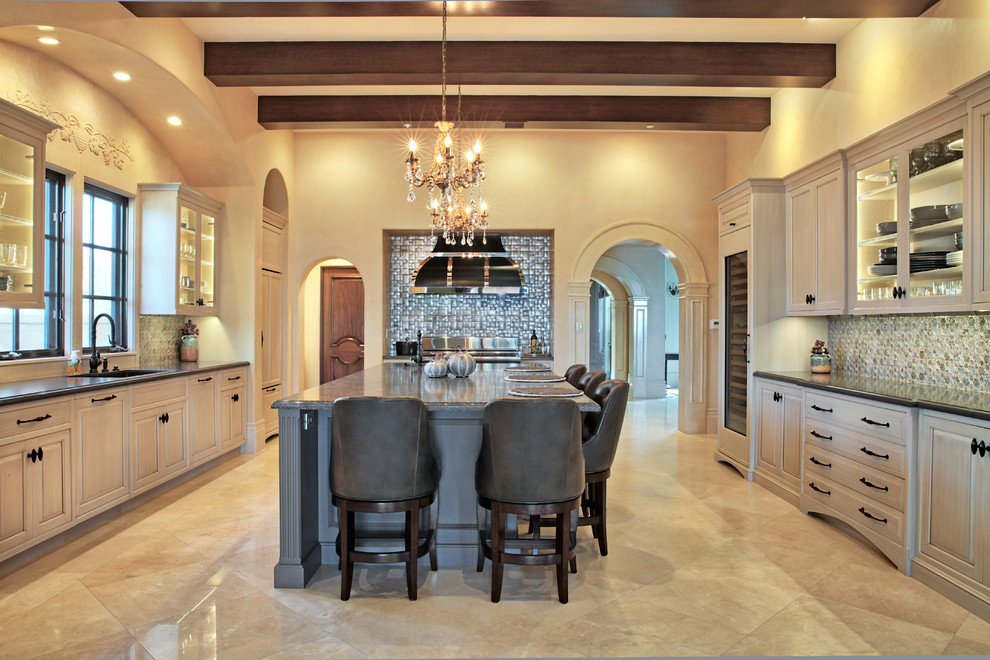 This is an example of a large traditional u-shaped eat-in kitchen in Orange County with an undermount sink, raised-panel cabinets, beige cabinets, quartz benchtops, metallic splashback, mosaic tile splashback, panelled appliances, travertine floors, with island, beige floor and grey benchtop.