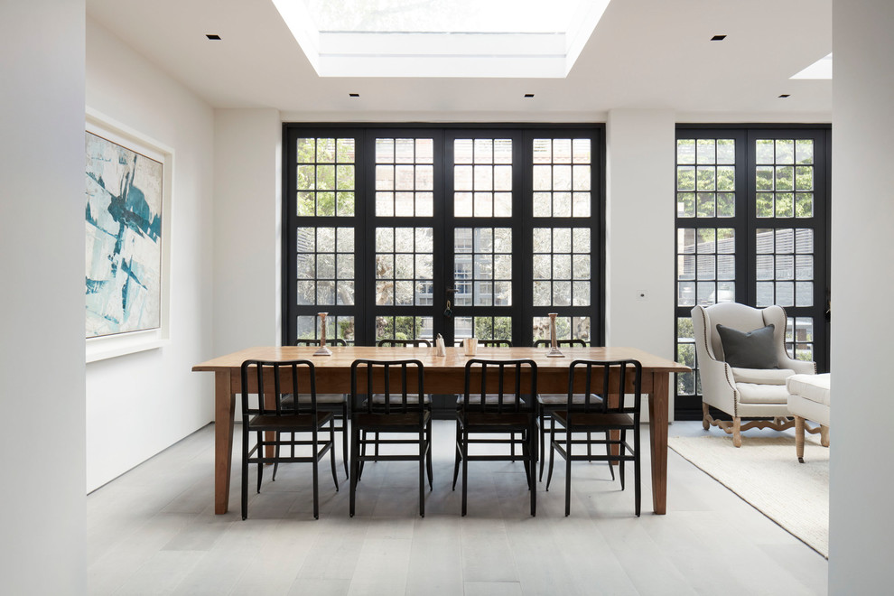 Photo of a mid-sized contemporary dining room in London with white walls, light hardwood floors and grey floor.