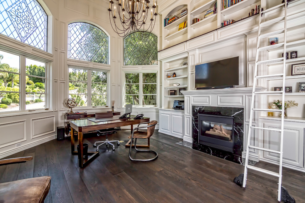 Mid-sized traditional study room in Los Angeles with white walls, dark hardwood floors, a standard fireplace and a freestanding desk.