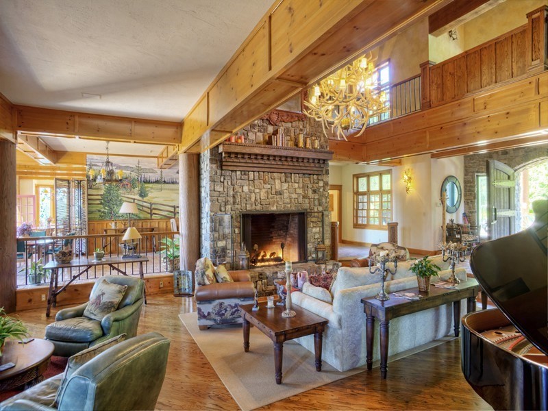 Photo of a mid-sized country open concept living room in Seattle with brown walls, dark hardwood floors, a standard fireplace, a stone fireplace surround and no tv.