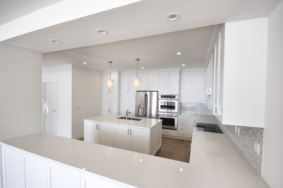 Inspiration for a large transitional u-shaped eat-in kitchen in Los Angeles with a double-bowl sink, shaker cabinets, white cabinets, marble benchtops, green splashback, mosaic tile splashback, stainless steel appliances, light hardwood floors and with island.