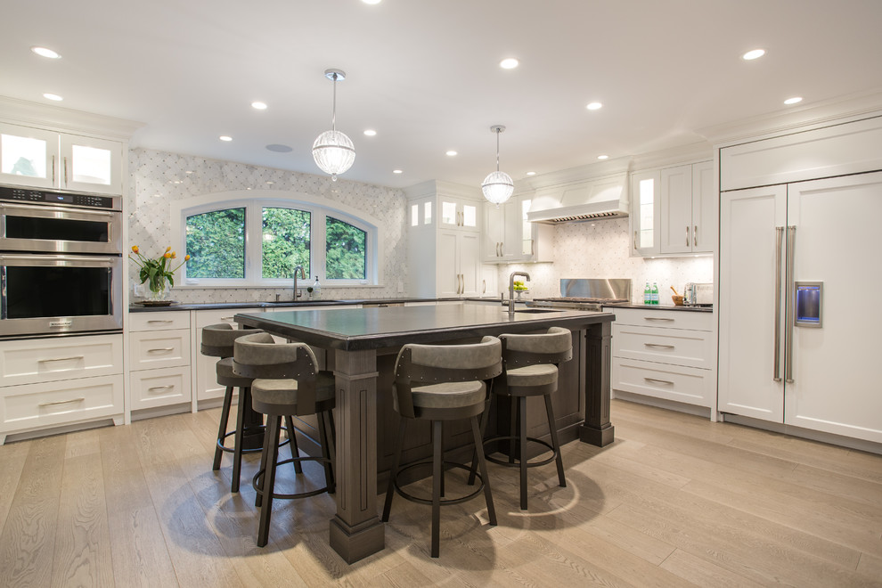 Large transitional l-shaped medium tone wood floor and beige floor eat-in kitchen photo in Vancouver with an undermount sink, shaker cabinets, white cabinets, granite countertops, gray backsplash, marble backsplash, stainless steel appliances, an island and black countertops