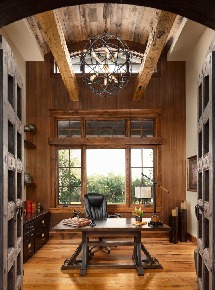 Imagen de despacho abovedado rústico grande con paredes beige, suelo de madera en tonos medios, escritorio independiente y suelo multicolor
