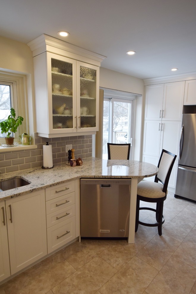 Example of a mid-sized transitional u-shaped ceramic tile enclosed kitchen design in Ottawa with an undermount sink, shaker cabinets, white cabinets, granite countertops, gray backsplash, glass tile backsplash, stainless steel appliances and a peninsula