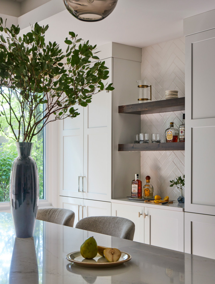 Eat-in kitchen - large transitional u-shaped light wood floor, brown floor and coffered ceiling eat-in kitchen idea in Chicago with a farmhouse sink, shaker cabinets, white cabinets, quartz countertops, white backsplash, subway tile backsplash, stainless steel appliances, an island and multicolored countertops