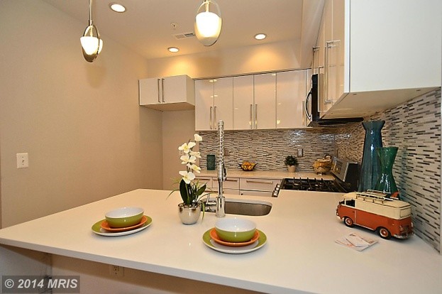 Example of a transitional u-shaped light wood floor eat-in kitchen design in DC Metro with an undermount sink, flat-panel cabinets, white cabinets, quartz countertops, multicolored backsplash, mosaic tile backsplash, stainless steel appliances and a peninsula
