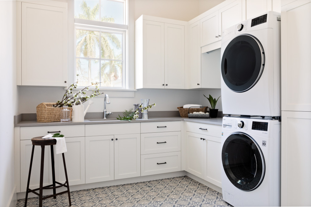 Design ideas for a large beach style l-shaped utility room in Tampa with a belfast sink, recessed-panel cabinets, white cabinets, white walls and grey worktops.