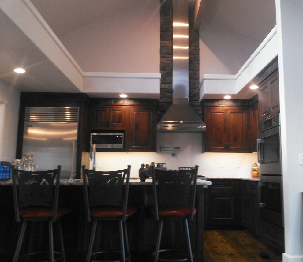 Example of a mid-sized mountain style l-shaped dark wood floor open concept kitchen design with an undermount sink, beaded inset cabinets, dark wood cabinets, granite countertops, stainless steel appliances and an island