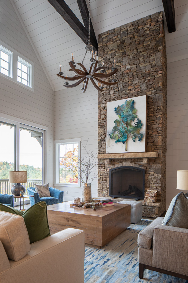 This is an example of a large country open concept living room in Other with medium hardwood floors, a standard fireplace, a stone fireplace surround, no tv, exposed beam and planked wall panelling.