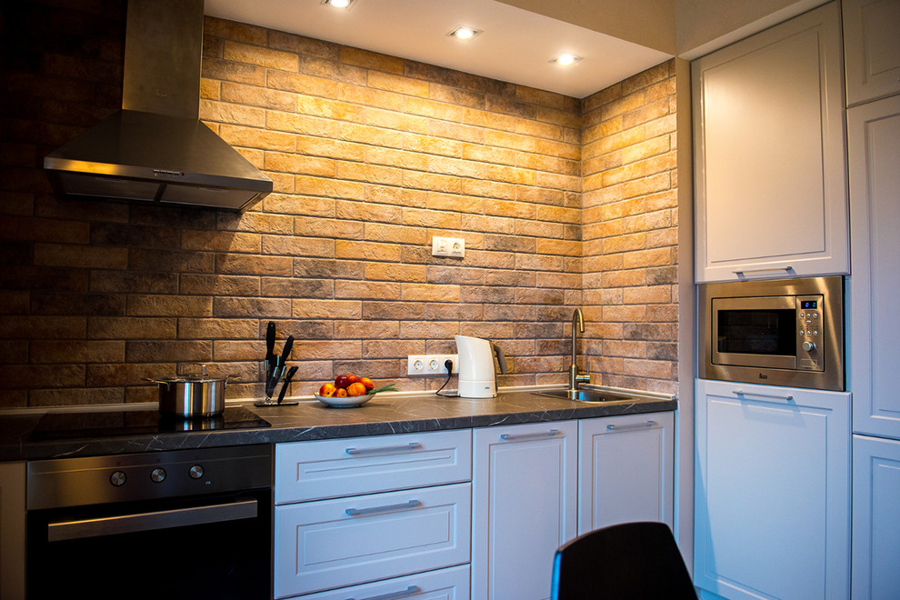 This is an example of a small single-wall eat-in kitchen in Saint Petersburg with a single-bowl sink, raised-panel cabinets, grey cabinets, solid surface benchtops, beige splashback, brick splashback, black appliances, porcelain floors, no island and grey floor.