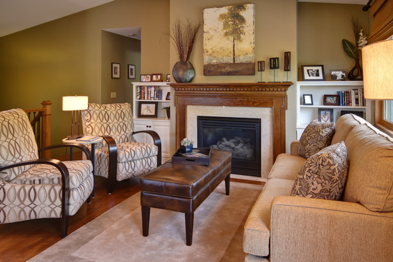 Traditional living room in Minneapolis with green walls, medium hardwood floors, a standard fireplace, a stone fireplace surround and no tv.