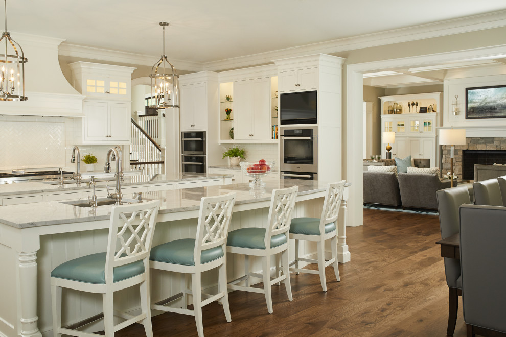 Inspiration for a large traditional l-shaped eat-in kitchen in Grand Rapids with flat-panel cabinets, white cabinets, quartz benchtops, white splashback, subway tile splashback, stainless steel appliances, dark hardwood floors, multiple islands, brown floor and grey benchtop.