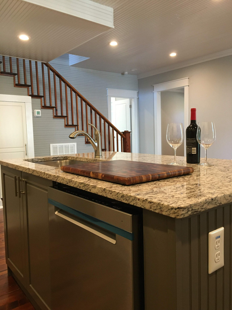 This is an example of a mid-sized arts and crafts l-shaped eat-in kitchen in Raleigh with an undermount sink, shaker cabinets, white cabinets, quartzite benchtops, white splashback, subway tile splashback, stainless steel appliances, dark hardwood floors, with island, brown floor and grey benchtop.