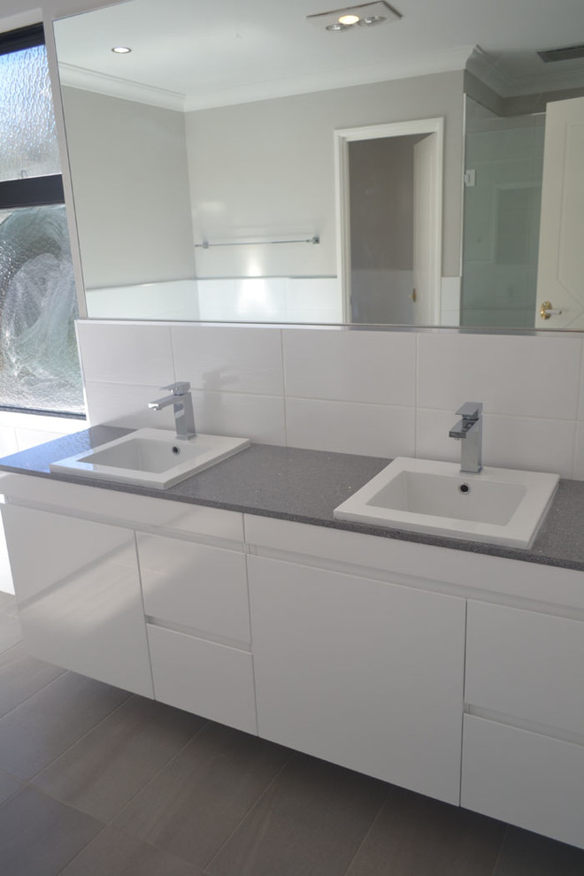 Contemporary bathroom in Perth with a drop-in sink, a freestanding tub, white tile and beige walls.