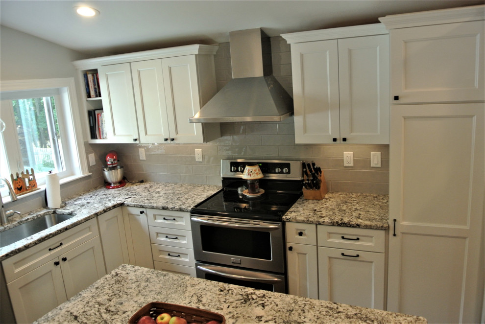 Inspiration for a transitional l-shaped medium tone wood floor and brown floor eat-in kitchen remodel in Boston with an undermount sink, shaker cabinets, white cabinets, granite countertops, beige backsplash, subway tile backsplash, stainless steel appliances, an island and beige countertops